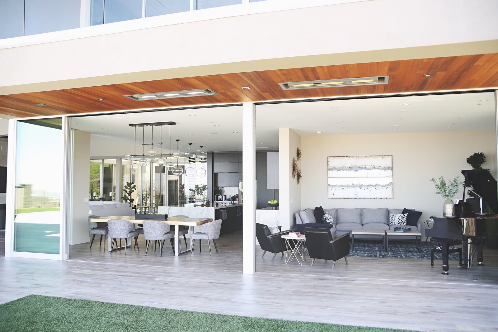 Covered outdoor living room opening to a lawn at a Widespread custom home
