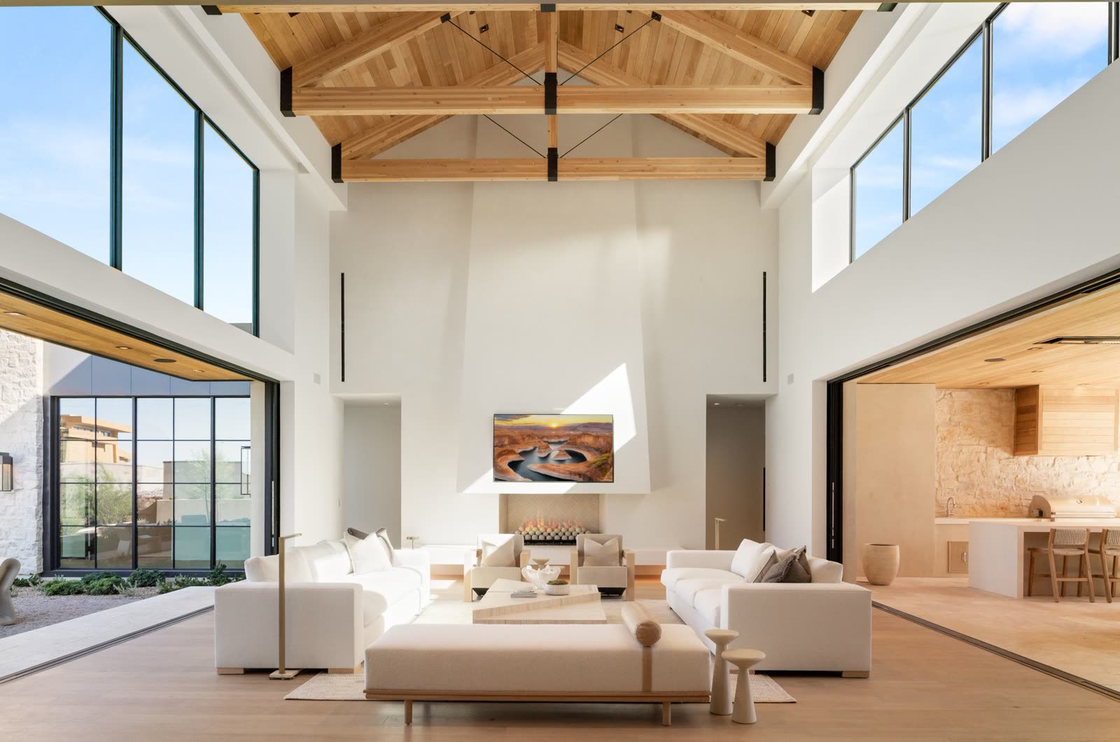 Great room with exposed timber trusses and a double-height window wall