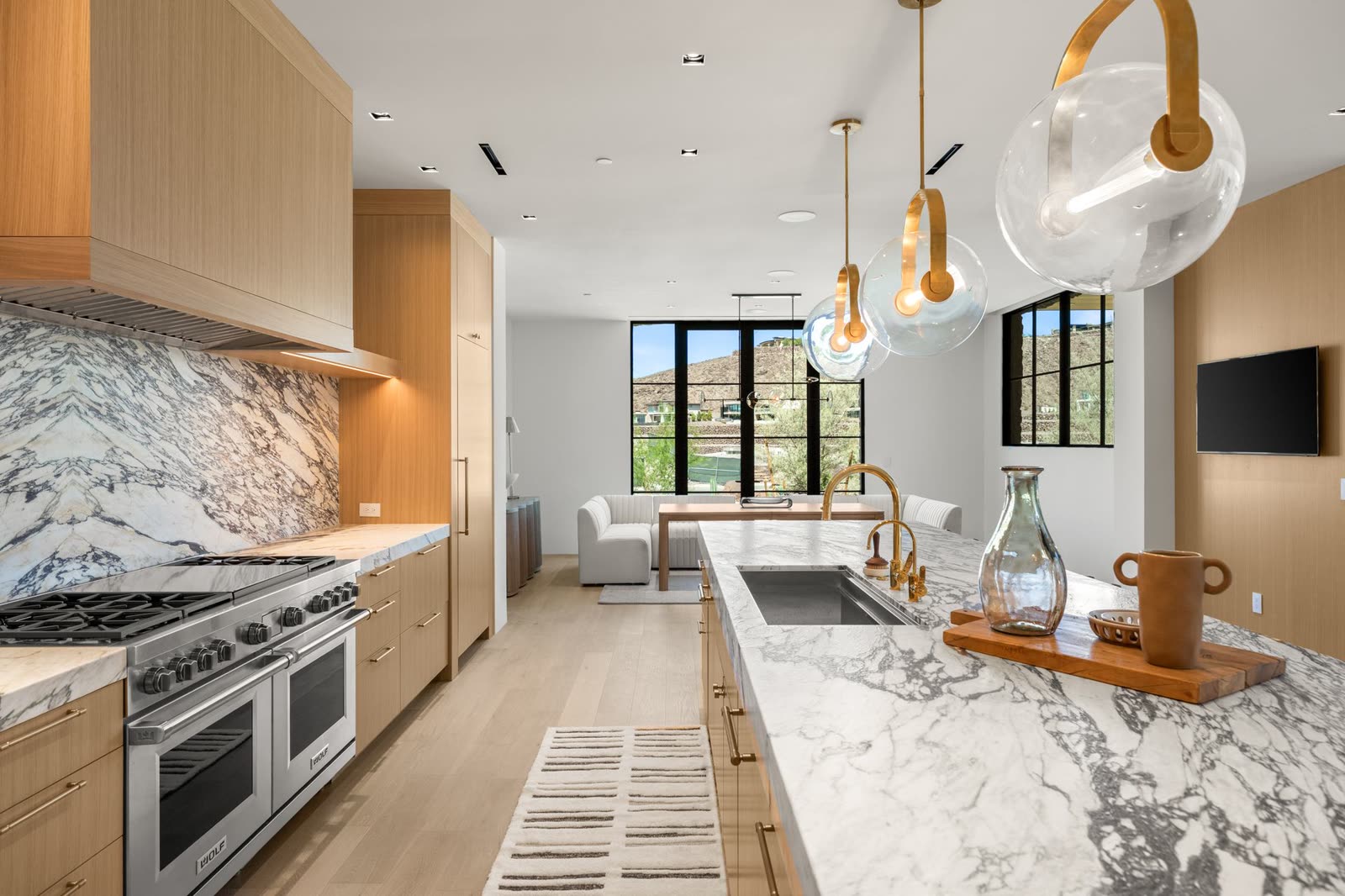 Kitchen with a book-matched stone backsplash and brass pendants